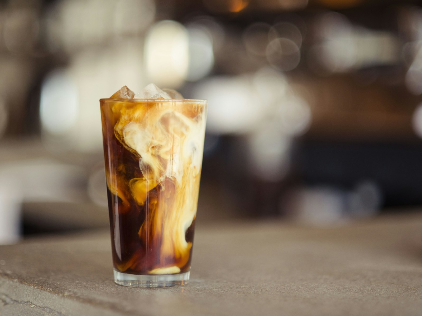 Iced cold brew swirling with oat beverage over ice